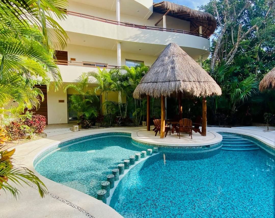 Edificio de dos niveles con palapa y alberca al frente