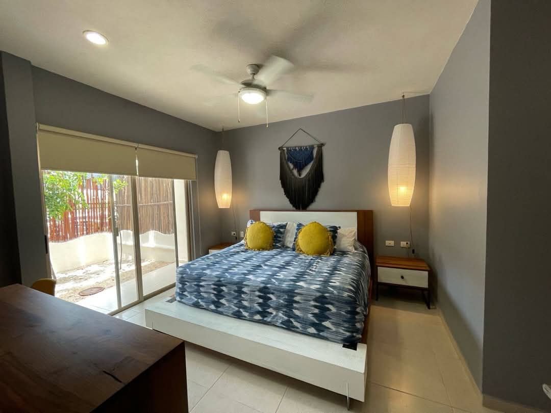 Recámara con una cama, ventilador de techo y puerta de vidrio