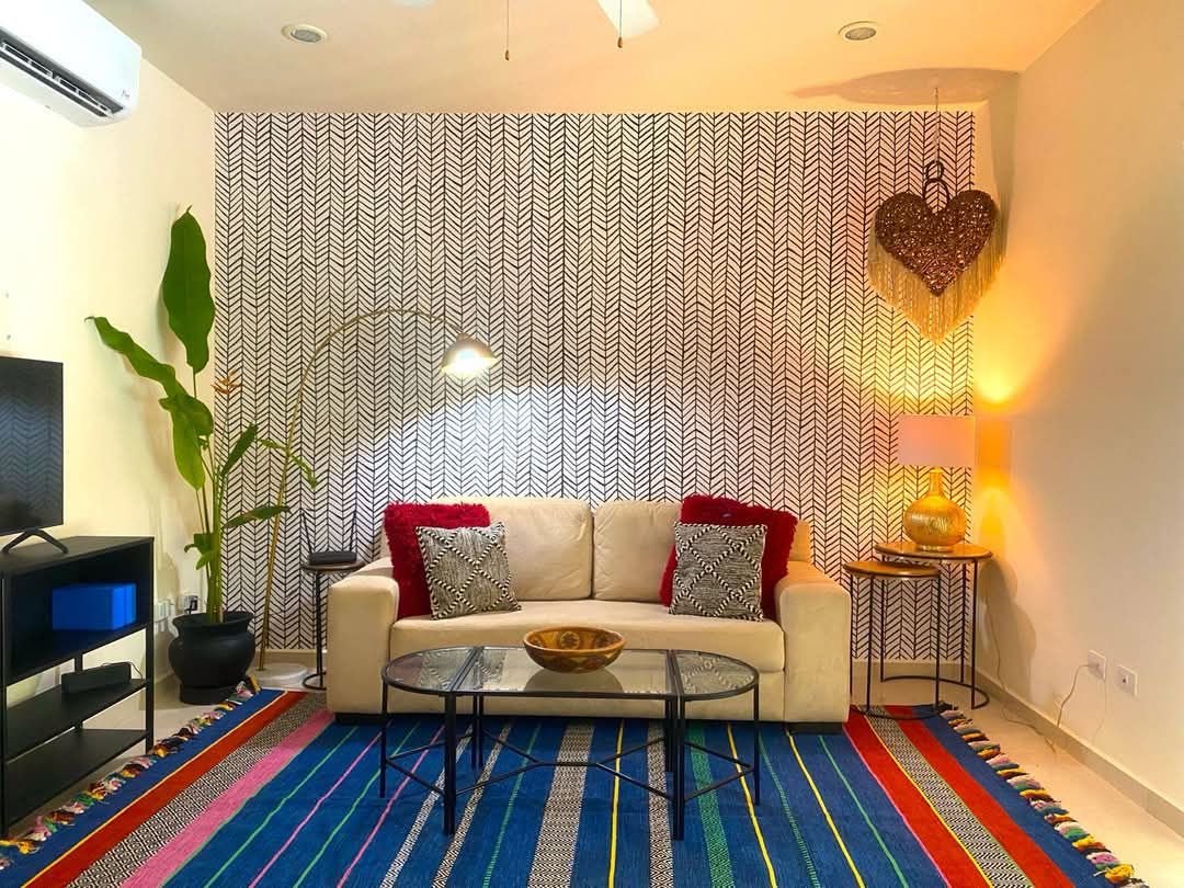 Sala con sofá claro, alfombra de rayas y televisión
