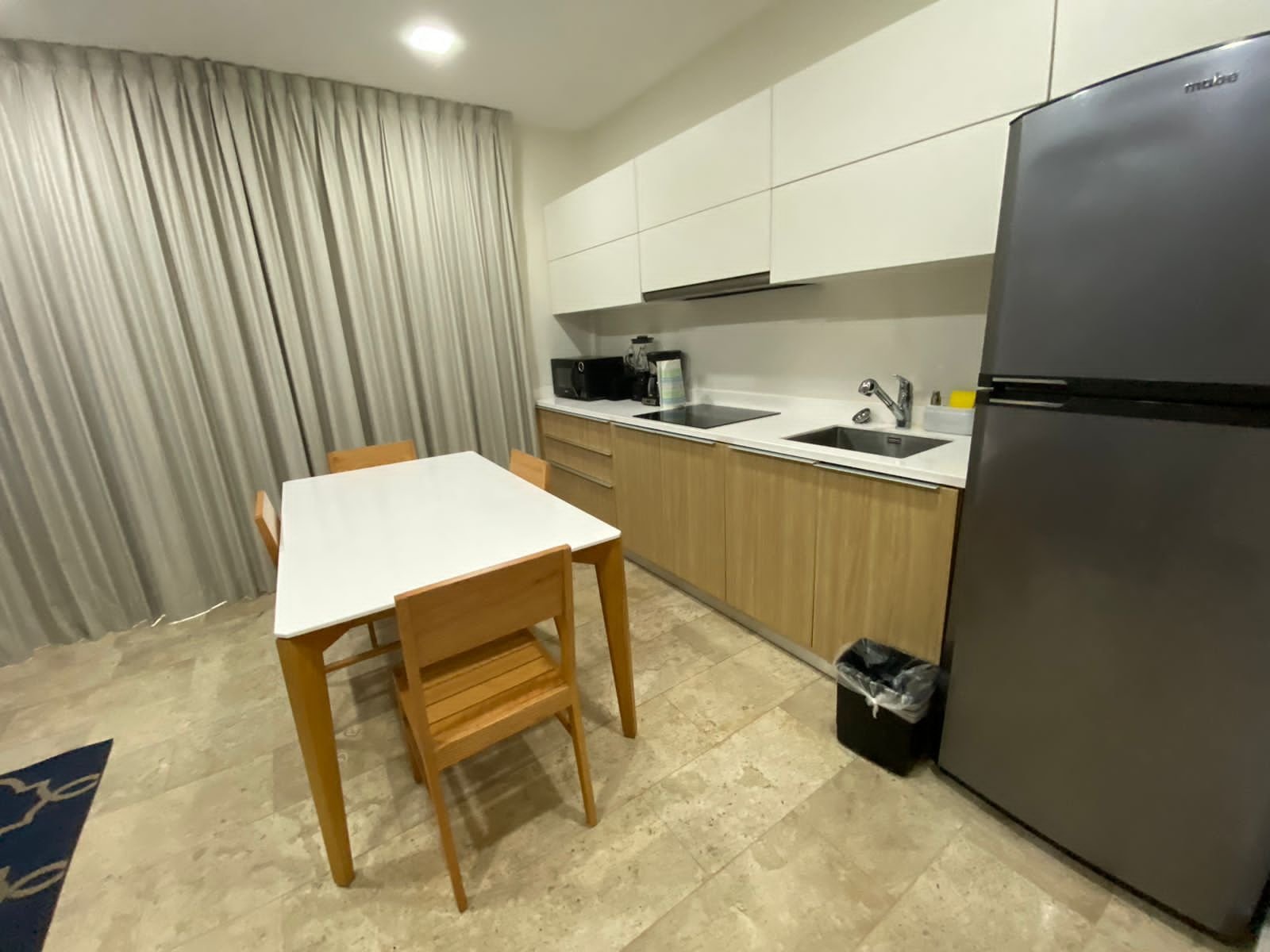 Cocina con estufa eléctrica, tarja, refrigerador y mesa de comedor