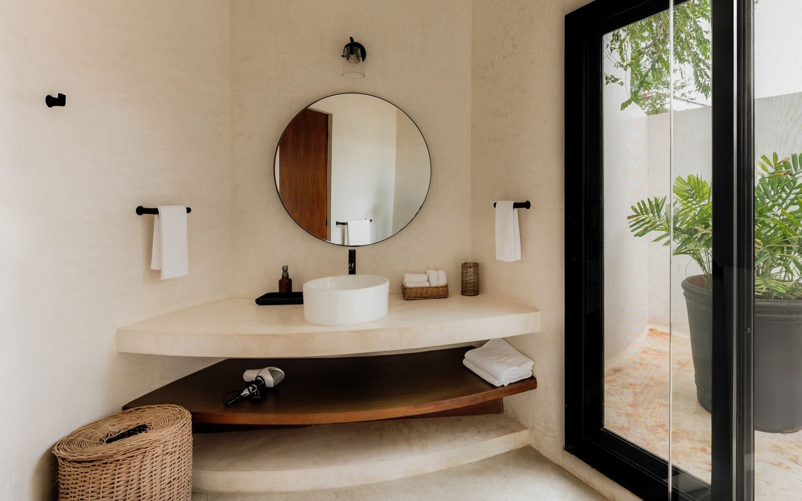Baño con lavabo blanco, espejo redondo y toallas