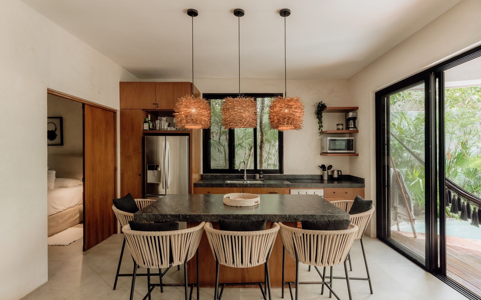 Barra de cocina con sillas tejidas, refrigerador y vista a la alberca