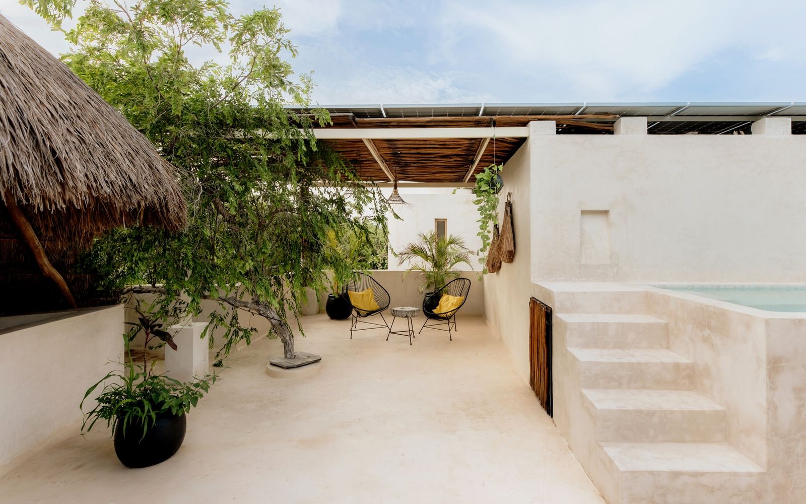 Patio con palapa, sillas y escalones hacia la alberca