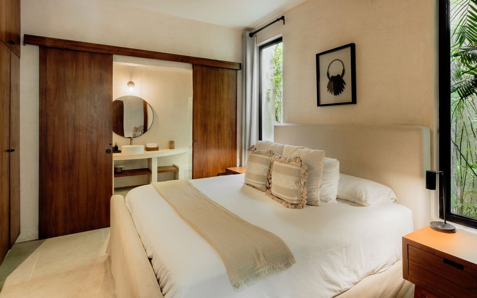 Recámara con cama amplia y puerta corrediza hacia un lavabo