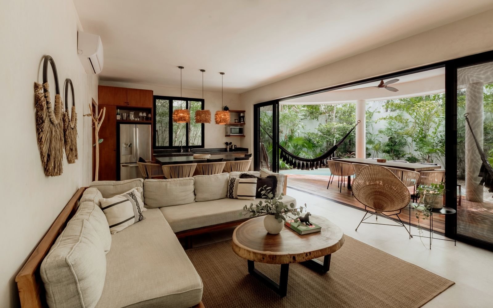 Sala con sofá claro, cocina al fondo y salida a la terraza
