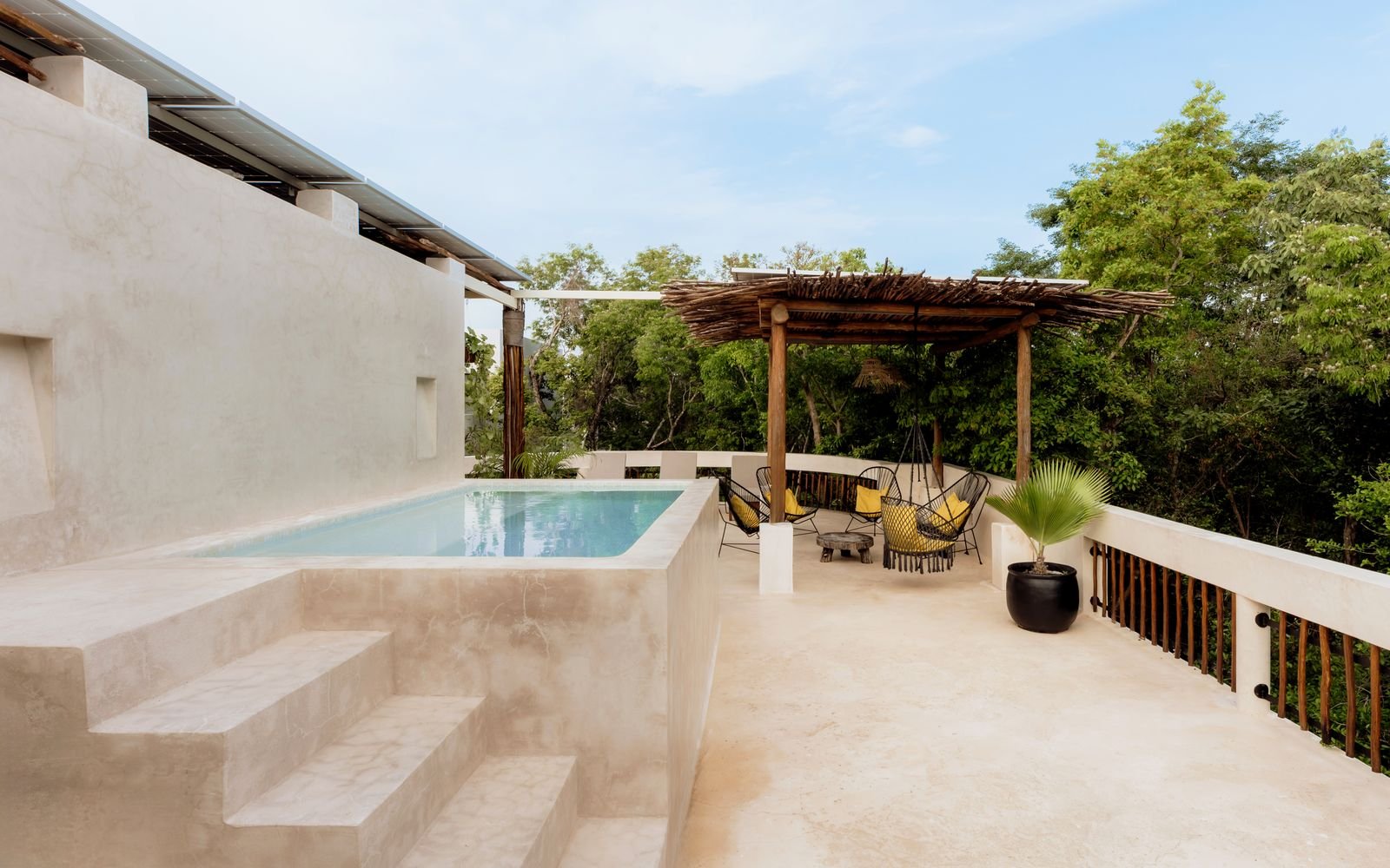 Terraza con alberca pequeña, pérgola de ramas y paneles solares en el techo
