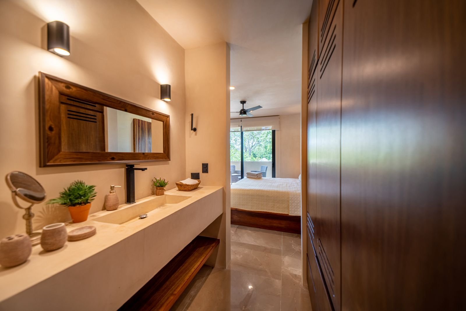 Baño con lavabo largo, espejo de marco de madera y repisa