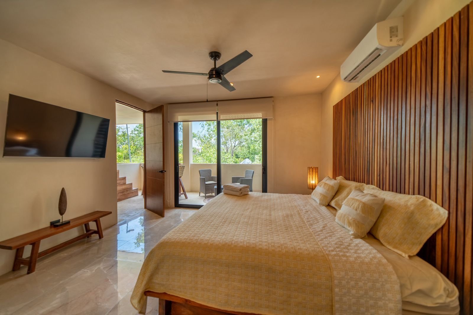 Recámara con una cama, televisión y muro de duelas