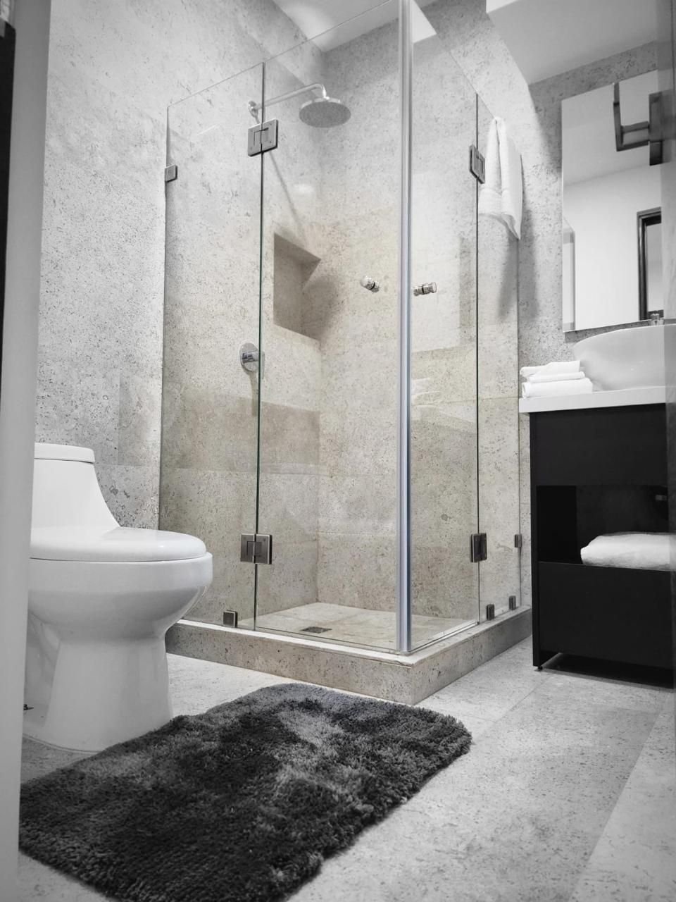 Baño con cancel de cristal, lavabo e inodoro