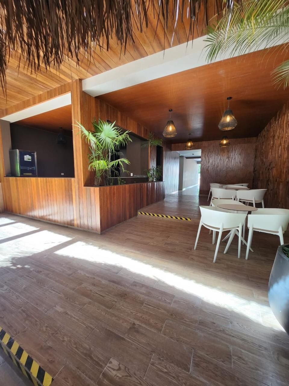 Zona con barra de madera, mesas blancas y sillas