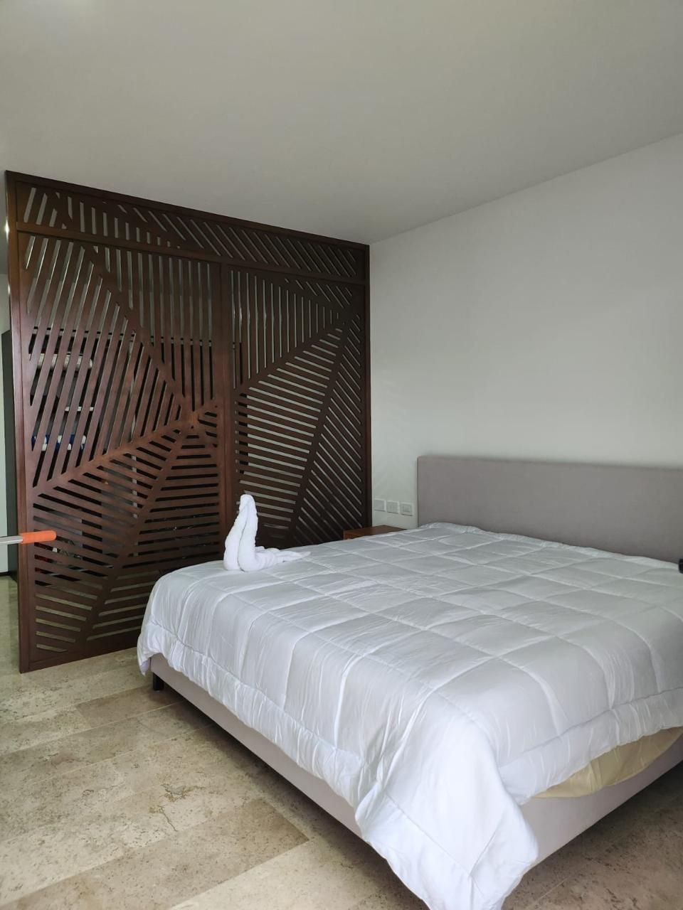 Misma recámara, con una celosía de madera junto a la cama