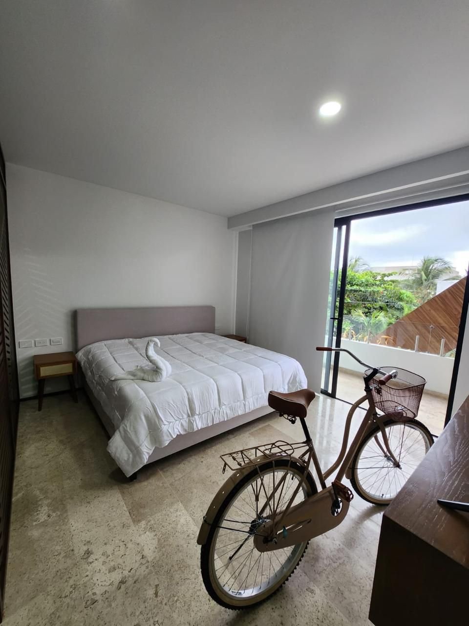 Recámara con cama, ventanal y una bicicleta junto a la ventana