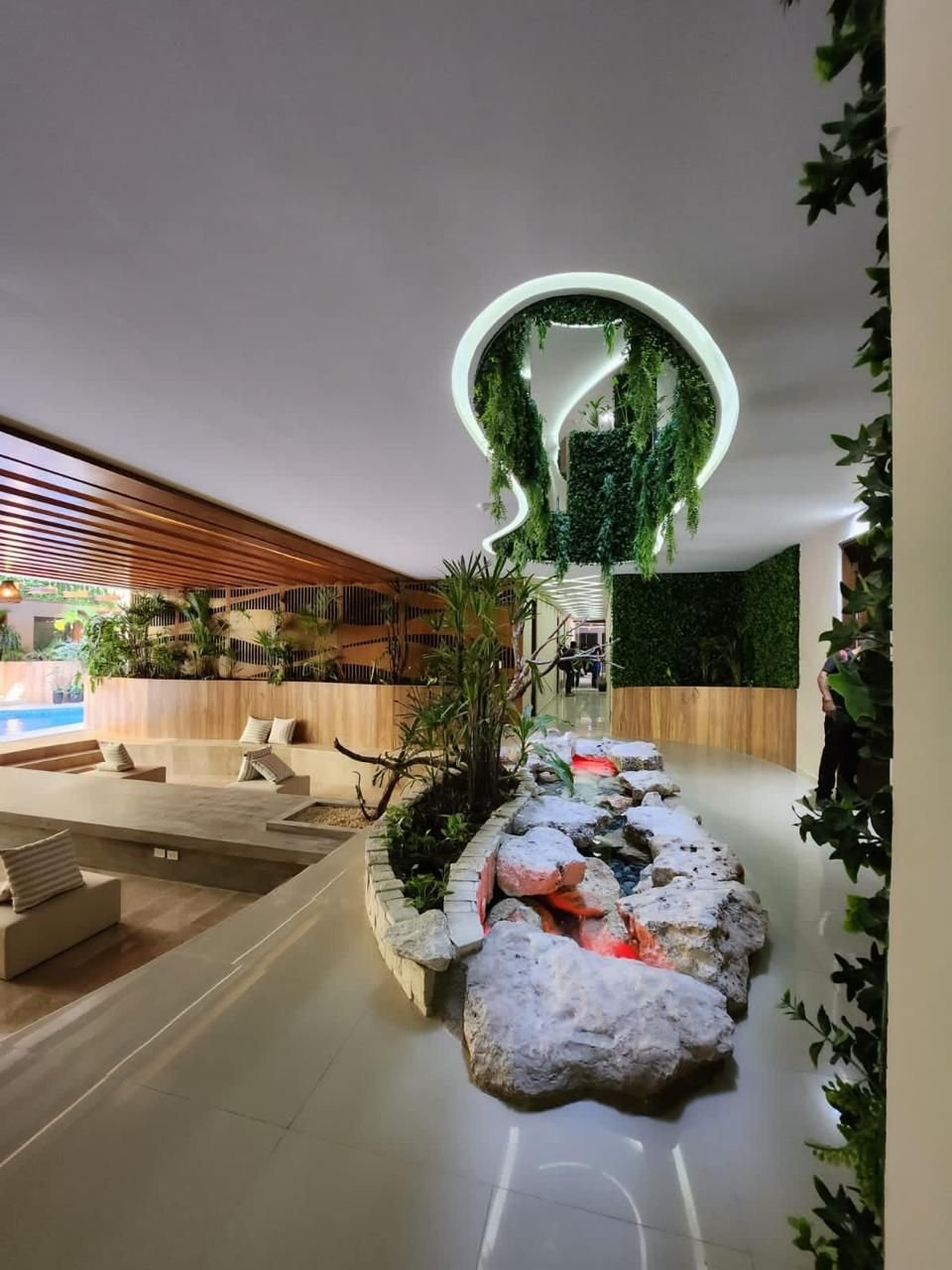 Vestíbulo con un canal de piedras, plantas, bancas y luz en el techo