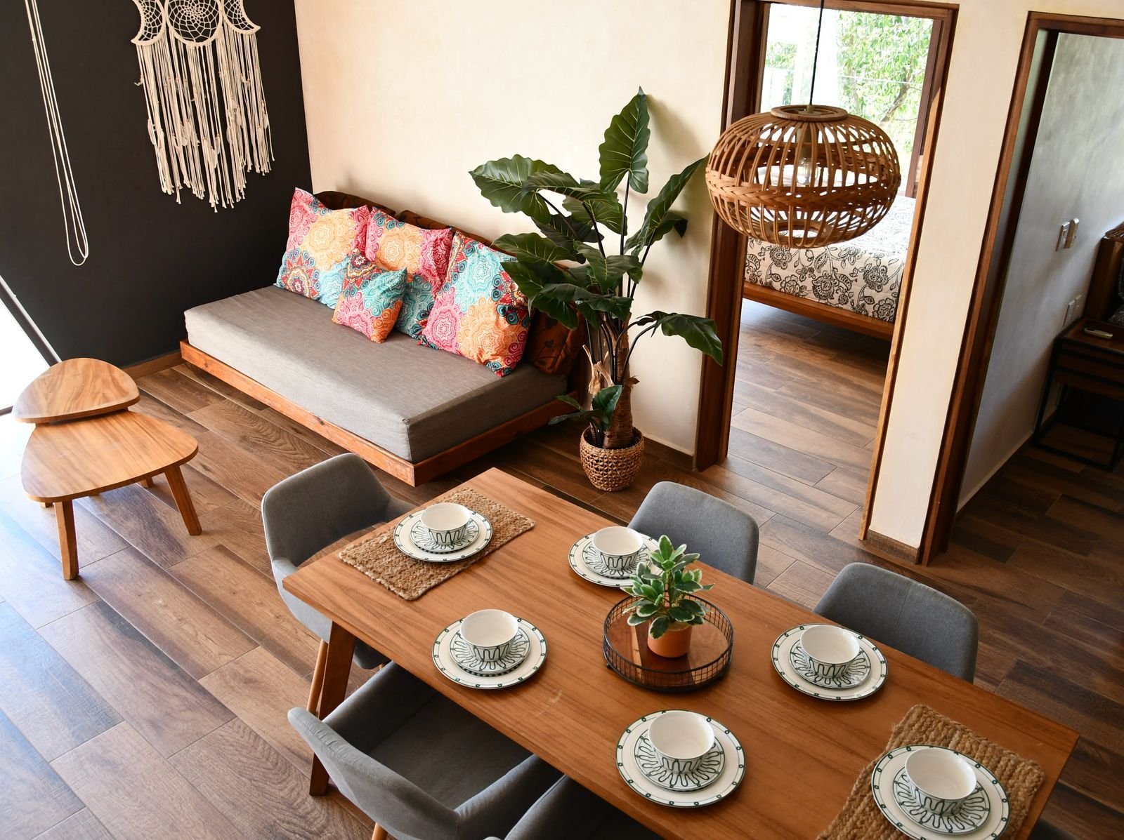 Comedor con mesa de madera, platos puestos y un sofá de colores