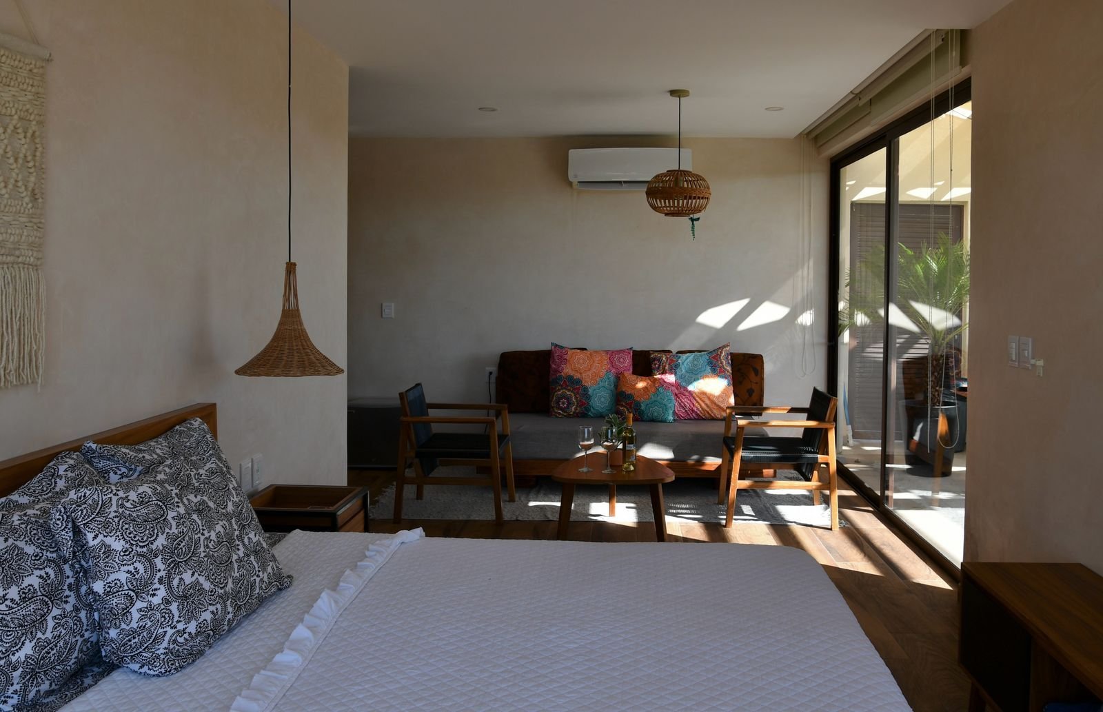 Recámara con cama que abre hacia una sala con sofá de colores
