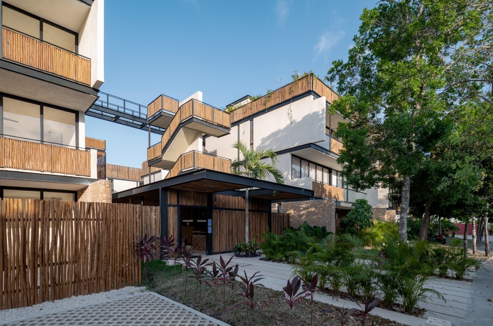 Edificio con barandales de palos, un puente entre volúmenes y jardín