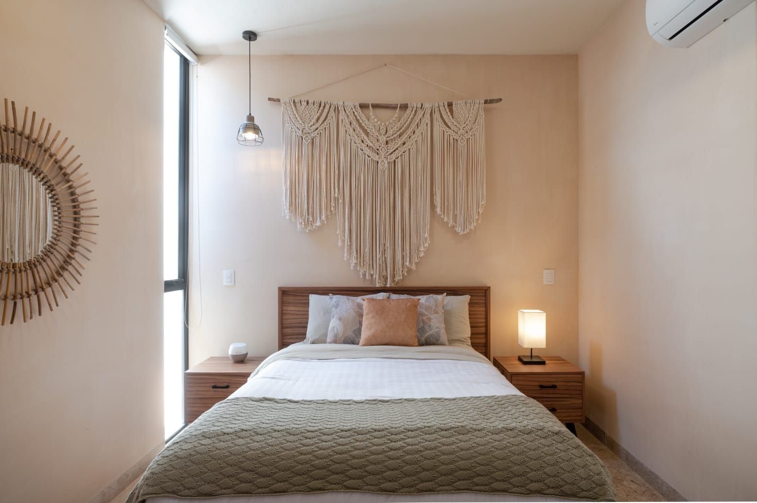 Otra recámara con cabecera de madera, colcha verde y un macramé ancho