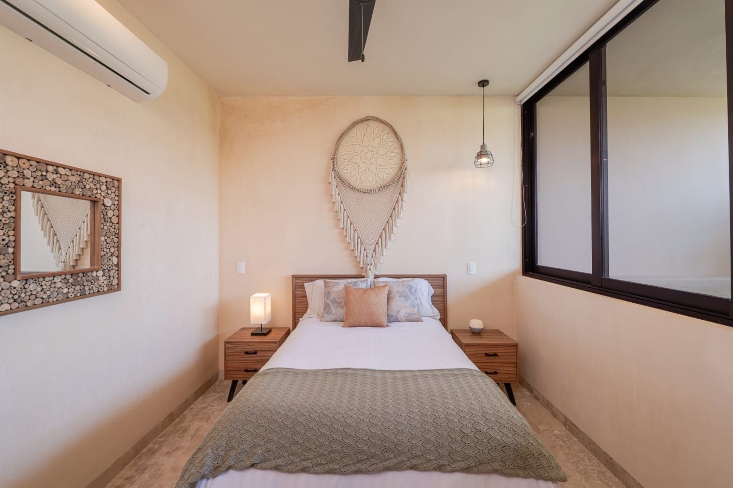 Recámara con cabecera de madera, colcha verde y un tejido oval en la pared
