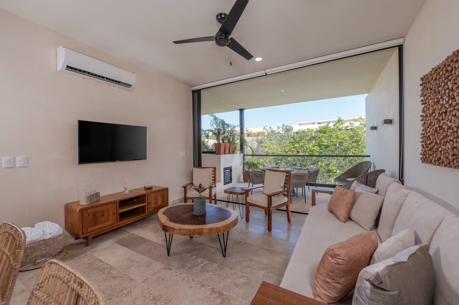 Sala con sofá claro, televisión y puerta hacia una terraza